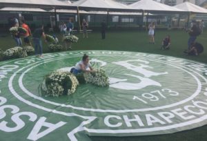 Funcionária da Chapecoense arruma flores decorativas sob distintivo da Chape, na Arena Condá (Foto: Felippe Costa)